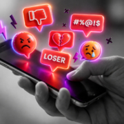 Eine Hand hält ein Handy, über dessen Oberfläche Icons schweben, die digitale Gewalt darstelllen
